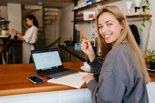 White blonde woman working with laptop while sitting in cafe