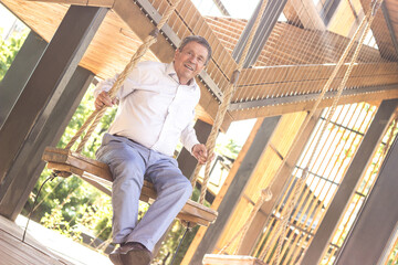 Smiling senior man swinging  at the playground