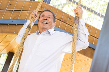 Smiling senior man swinging  at the playground