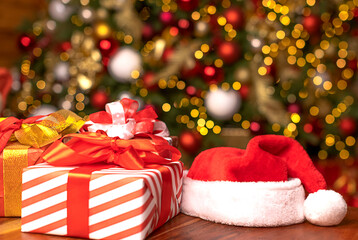 Santa hat and christmas gifts on the background of a beautiful defocus decorated Christmas tree background. Shopping store. Christmas and New Year concept