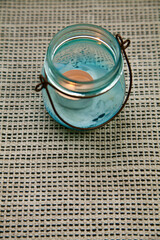Obraz na płótnie Canvas Eine Kerze in einem Glassbehälter auf einem Textiluntergrund