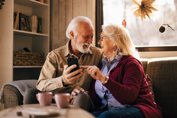 Lovely mature woman and man, looking at each other, sharing some online memories over the phone.