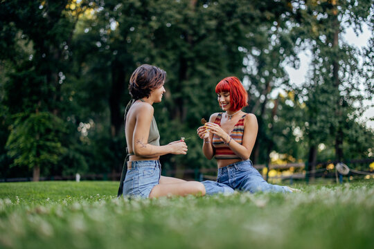 Two smiling lgbt girls, being outdoor, sitting on the grass.