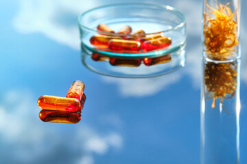 Calendula oil in capsules. Oil extracted from marigold flowers, dry flower petals on orange blue...
