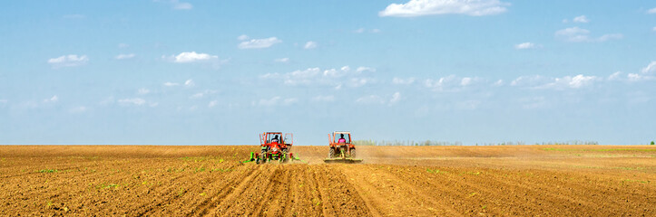 Fototapeta premium Farmers with tractors sowing on agricultural fields on sunny spring day 