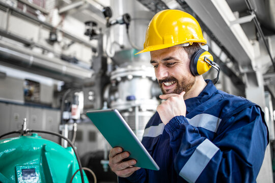 Close up portrait view of refinery operator standing by gas generator and controlling production.