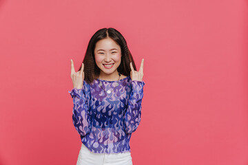 Young cute smiling asian girl showing rock gesture both hands