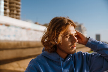 Young blonde man listening music while working out on sunrise