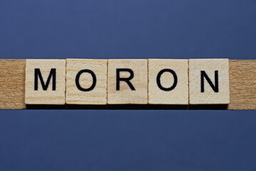text the word moron from brown wooden small letters on a black table