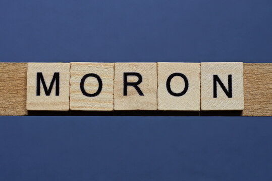 text the word moron from brown wooden small letters on a black table