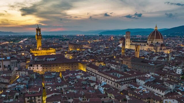 Sunset hyperlapse of old city. Gradual switching on of street lights at dusk. Forwards fly above historic sights in Florence, Italy