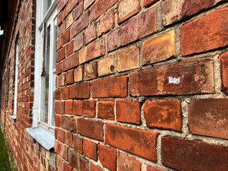 Wall of a building made with old red bricks and with windows with white frames. Selective focus