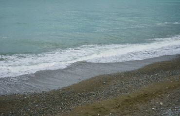 Sea shore with pebbles, wet sea pebbles on the beach and quiet sea surf