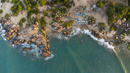 Ocean tropical landscape, rocky coast with fishing boats, drone shot, water and beach.