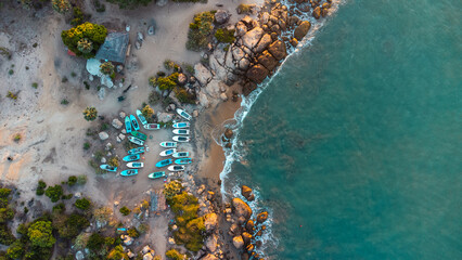 Ocean tropical landscape, rocky coast with fishing boats, drone shot, water and beach.