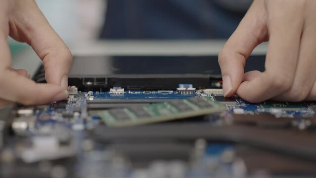 Close up hand of woman removing RAM random access memory from notebook or laptop. Fixing or repair computer.