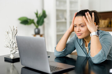 Female freelance is massaging head temples with suffering face expression. Tired and worn out from...