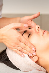 Young caucasian woman with closed eyes getting a facial massage in a beauty clinic