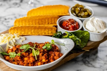 Plate of chickpea curry, delicious sauces and picked vegetables served with taco bread