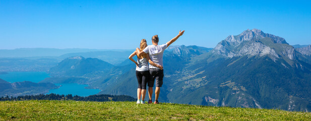 hiker couple enjoying panoramic view of mountain and annecy lake in France