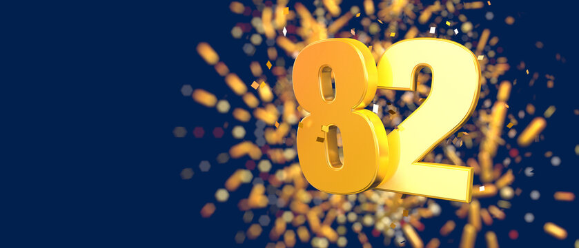 Gold number 82 in the foreground with gold confetti falling and fireworks behind out of focus