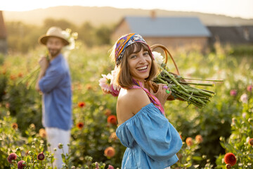 Portrait of a beautiful and cheerful woman as a farmer or gardener holding basket full of freshly...