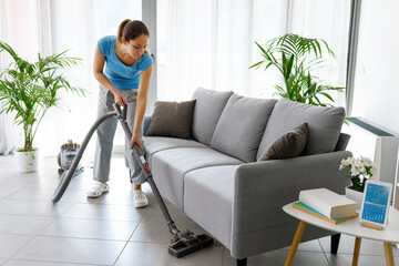Fototapeta na wymiar Woman vacuuming the floor at home