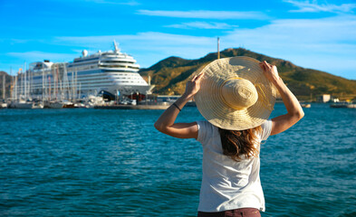 Fototapeta premium Woman with hat looking at sea and cruise boat
