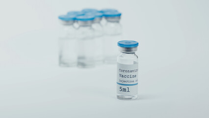 glass bottle with coronavirus vaccine lettering with blurred background on white.