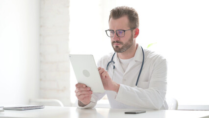 Doctor using Tablet while Sitting in Clinic