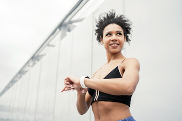 A sporty woman trains outside using a fitness watch.