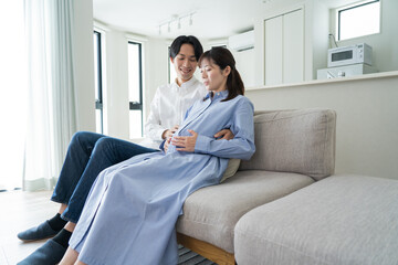 Fototapeta premium 自宅で笑顔でお腹をさする日本人夫婦