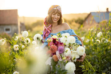 Portrait of a woman with lots of freshly picked up colorful dahlias and lush amaranth flower on...