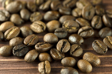 Roasted coffee beans on a wooden brown background, close-up.