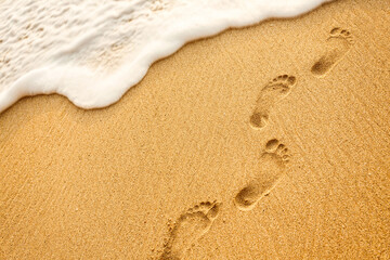 Beach, wave and footprints at sunset time