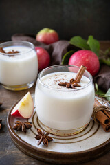 Homemade banana apple smoothie with apples, yogurt, cinnamon, spices or lassi in a glass on a rustic table.