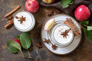 Autumn apple drink. Homemade banana apple smoothie with apples, yogurt, cinnamon, spices or lassi in a glass on a rustic table. View from above.