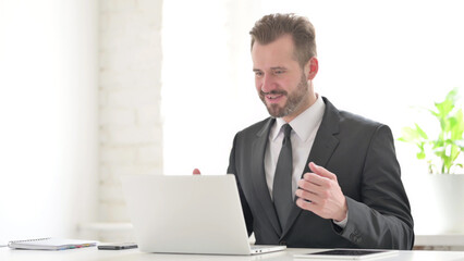 Young Businessman Celebrating Success while using Laptop in Office