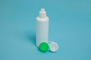 Packages with contact lenses, case and drops on blue background