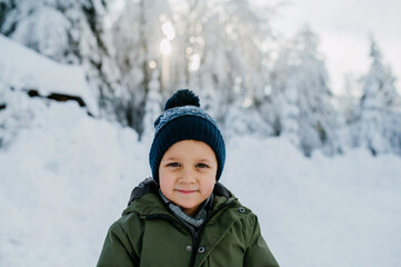 Fototapeta na wymiar Winter portrait of little boy in warm clothes, outdoors during winter day.