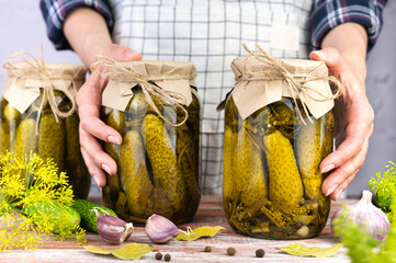 Woman's hands hold jars of preserved cucumbers. Delicious homemade pickled. Close-up.