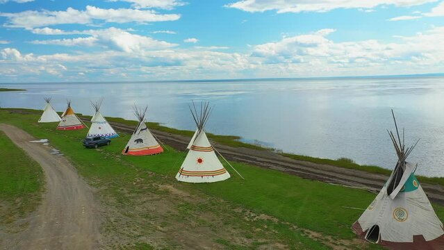 Aerial drone video, rotating from right to left revealing the landscape near the tipis facing a bay and the St-Lawrence River in Maria in Gaspesie, Quebec.
