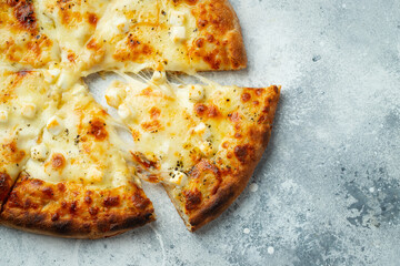 Italian pizza four cheeses with stretching cheese and basil on a light concrete background.
