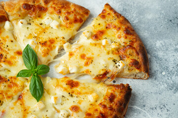 Italian pizza four cheeses with stretching cheese and basil on a light concrete background
