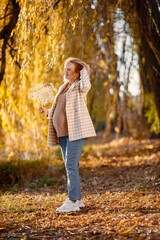 Caucasian mature pregnant woman standing in autumn park