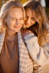 Portrait of mother and daughter hugging at autumn park
