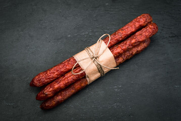 Polish thin, dry kabanosy sausages wrapped with eco food paper, tied with string, on black...