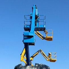 Three aerial working platforms  of cherry picker against blue sky. Back side for the first one and side view for the others two.  