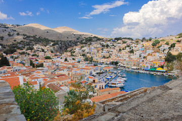 Fototapeta na wymiar Panoramic view, aerial skyline of small haven of Symi island. Village with tiny beach and colorful houses located on rock. Tops of mountains on Rhodes coast, Dodecanese, Greece . High quality photo