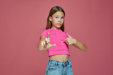 Worried child girl pointing by fingers on herself and showing amount size gesture, standing on pink studio background